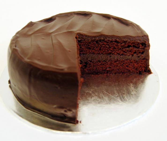 worker are sat around a table looking at a large chocolate cake